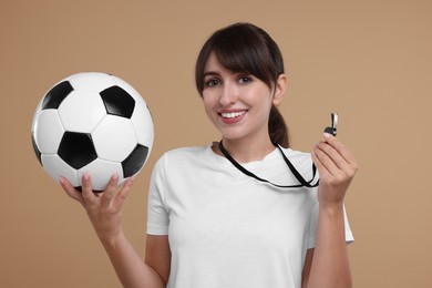 Happy woman with whistle and soccer ball on beige background