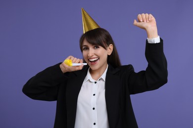 Woman in party hat with blower on purple background