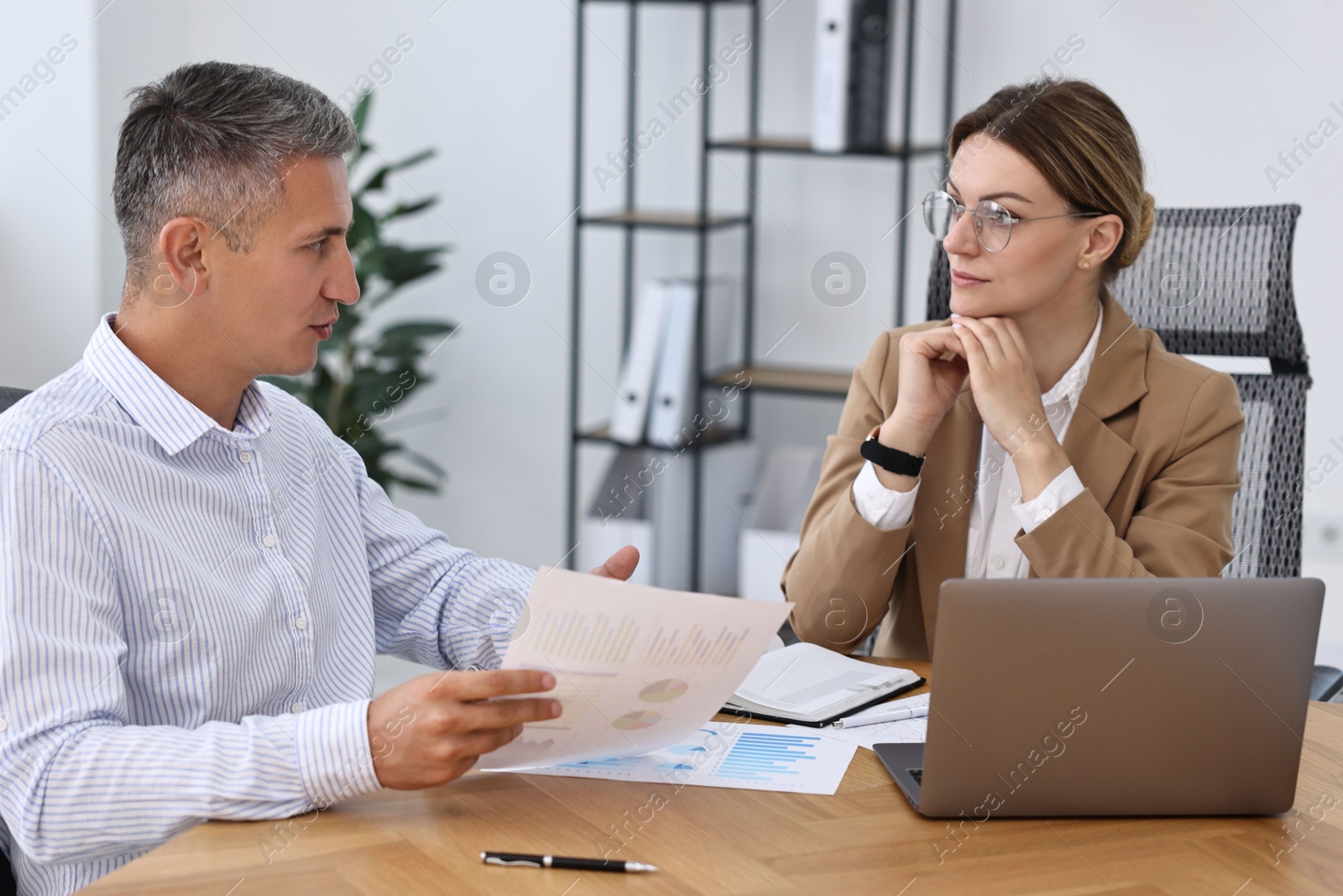 Photo of Banker working with client at wooden table in office