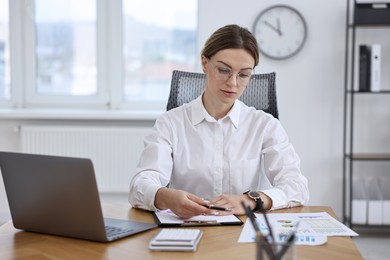 Photo of Banker working at wooden table in office