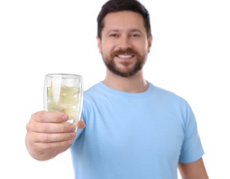 Photo of Happy man showing glass of water with lemon on white background, selective focus