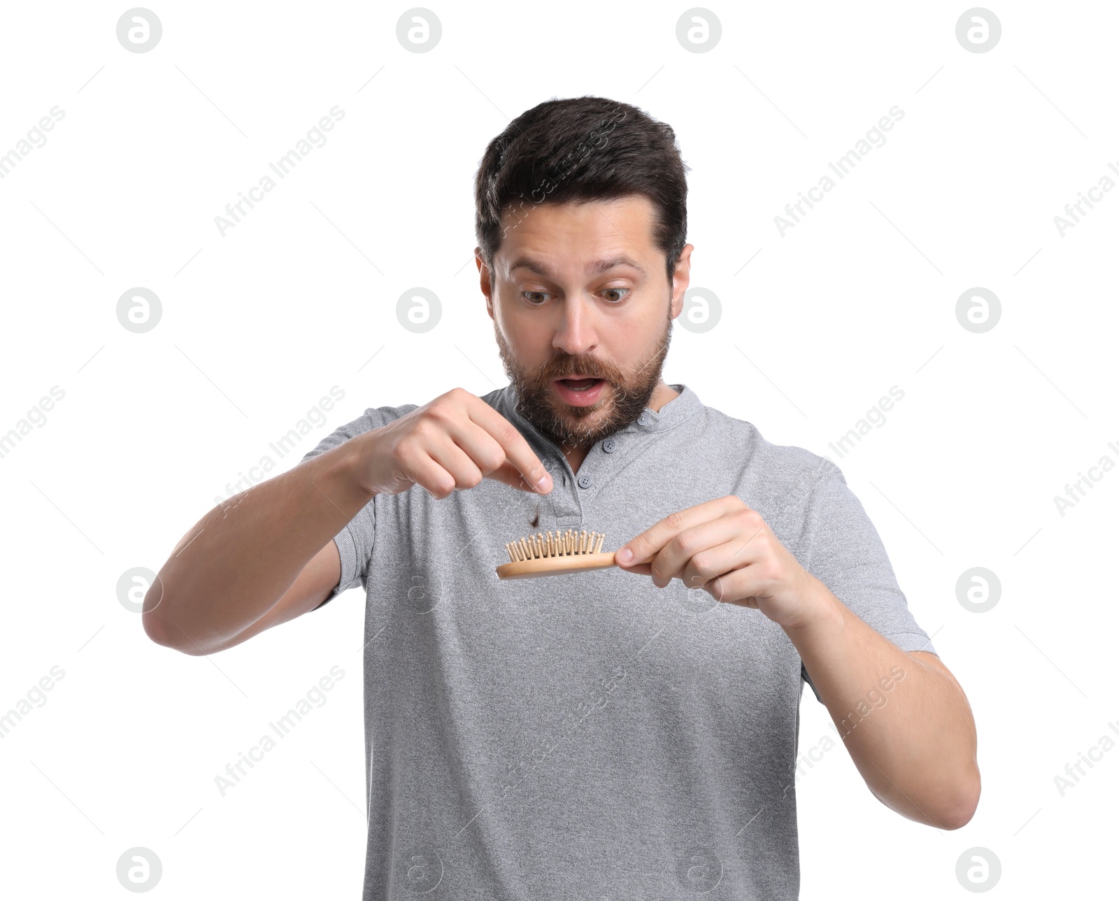 Photo of Emotional man taking his lost hair from brush on white background. Alopecia problem