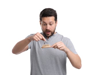 Emotional man taking his lost hair from brush on white background. Alopecia problem