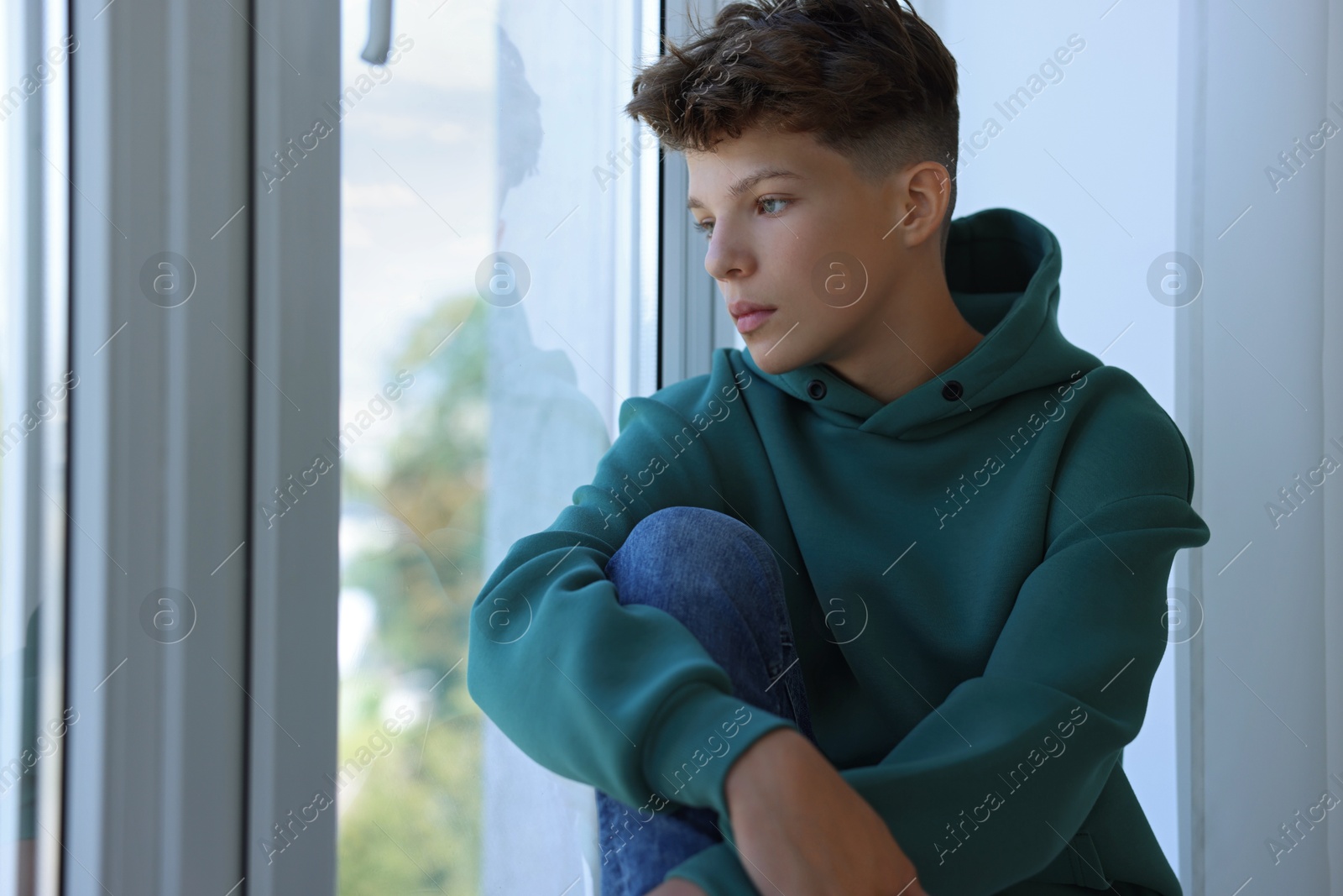 Photo of Loneliness concept. Sad teenage boy near window indoors