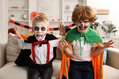 Funny children wearing costumes for Halloween celebration in room