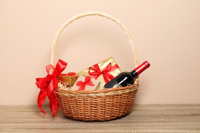 Photo of Wicker gift basket with wine on wooden table