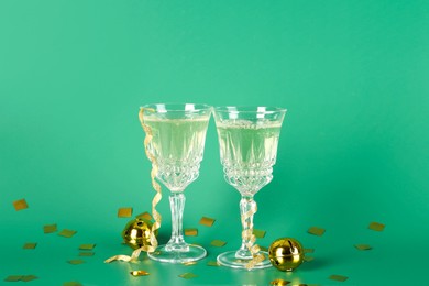 Photo of Sparkling wine in glasses, confetti and other Christmas decor on green background