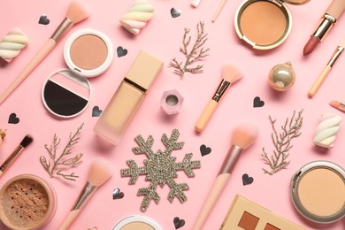 Photo of Different makeup brushes, decorative cosmetics and Christmas decor on pink background, flat lay