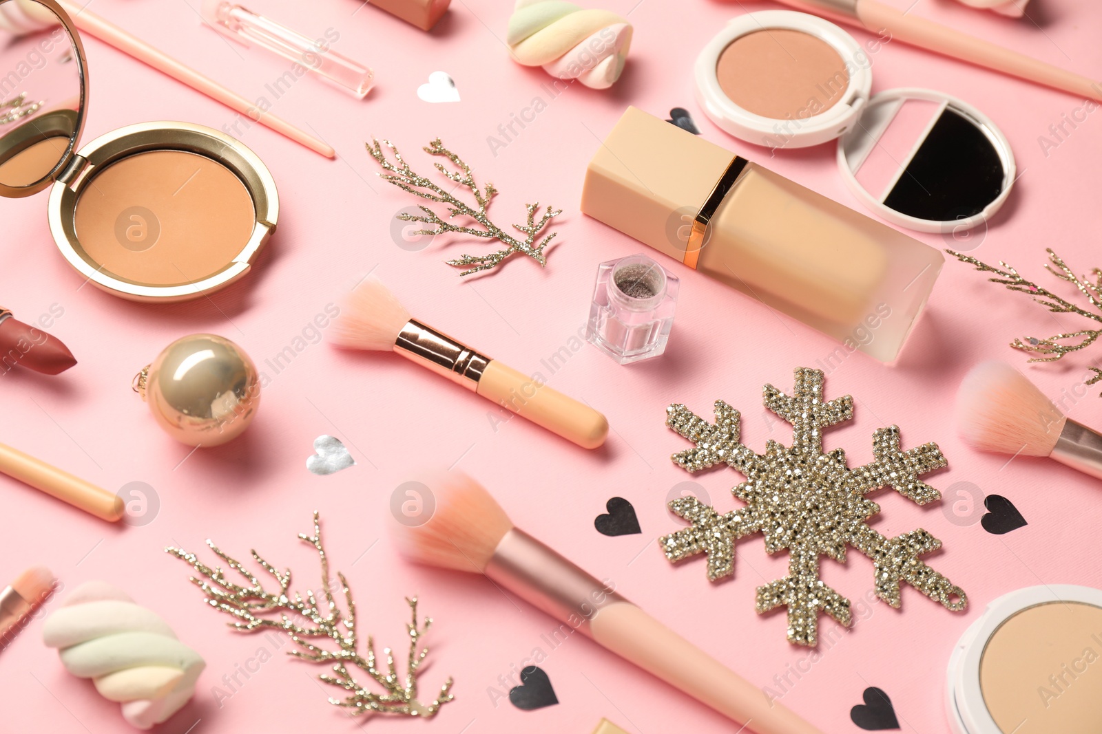 Photo of Different makeup brushes, decorative cosmetics and Christmas decor on pink background