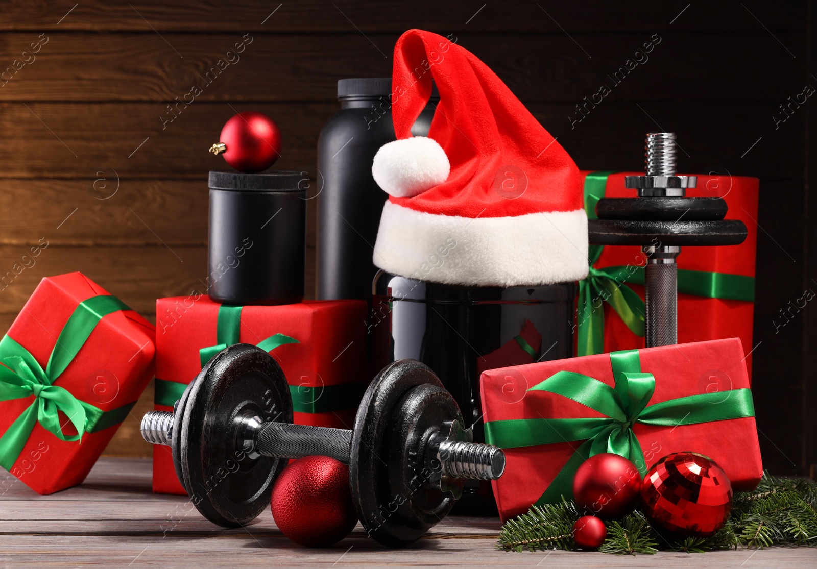 Photo of Dumbbells, containers with supplement and Christmas decor on wooden table