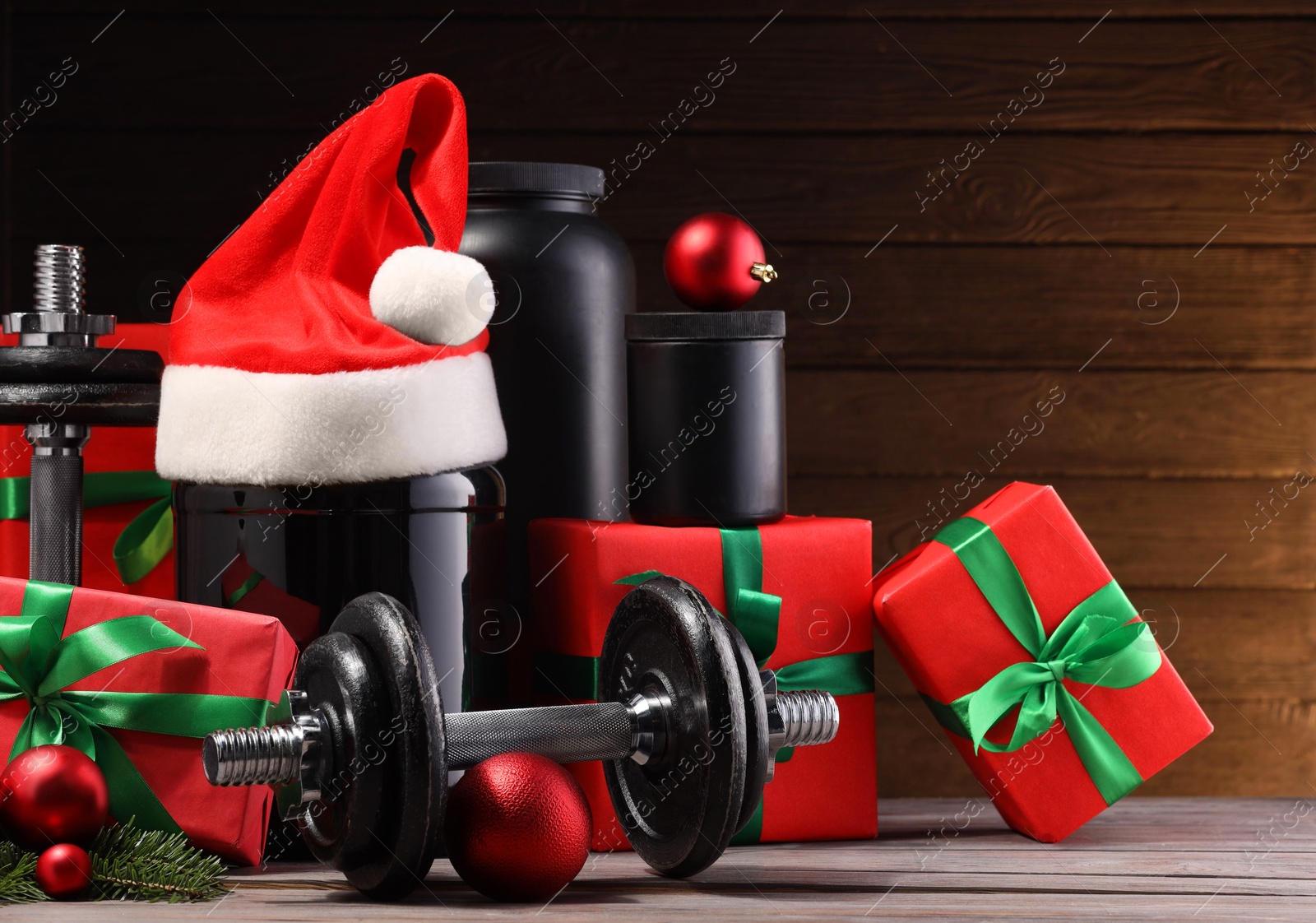 Photo of Dumbbells, containers with supplement and Christmas decor on wooden table