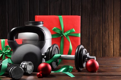 Photo of Dumbbells, container with supplement, kettlebell and Christmas decor on wooden table