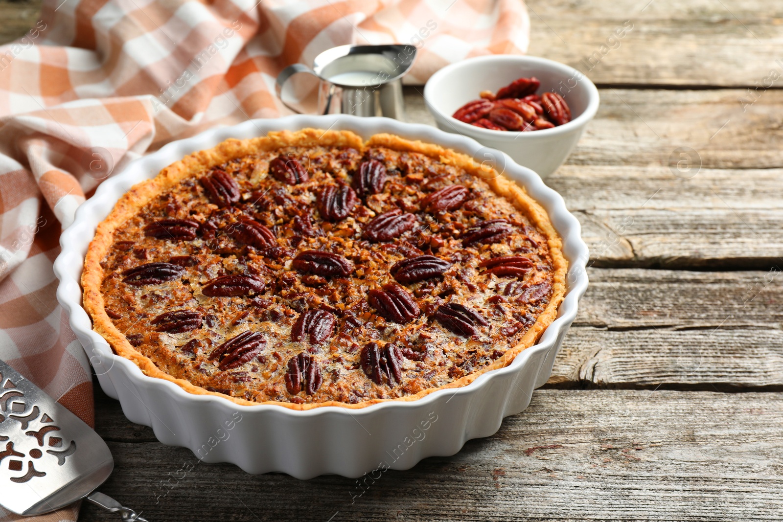 Photo of Delicious pecan pie in baking dish on wooden table, closeup