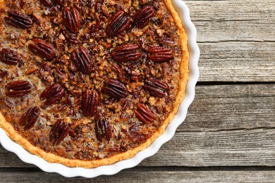 Photo of Delicious pecan pie in baking dish on wooden table, top view