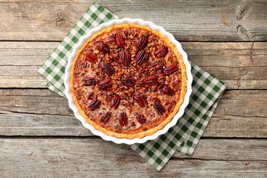 Photo of Delicious pecan pie in baking dish on wooden table, top view.