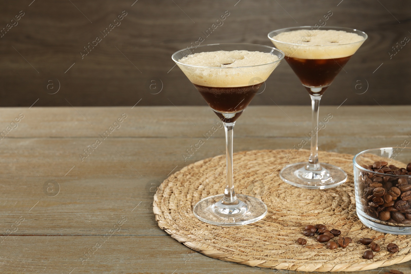 Photo of Glasses of fresh coffee cocktail and beans in bowl on wooden table, space for text