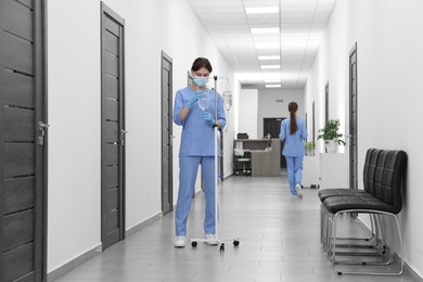 Photo of Nurse with IV drip in hospital hallway