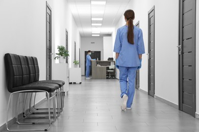 Photo of Nurse in uniform walking in hospital hallway, back view