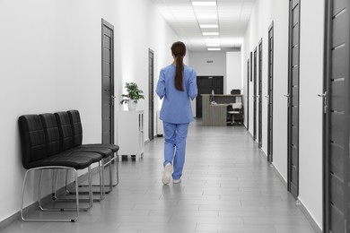 Nurse in uniform walking in hospital hallway, back view