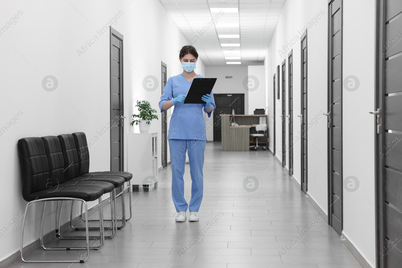 Photo of Nurse working with clipboard in hospital hallway