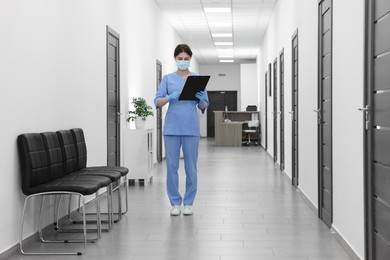 Nurse working with clipboard in hospital hallway