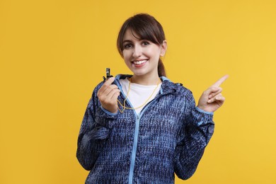 Happy woman with whistle on orange background