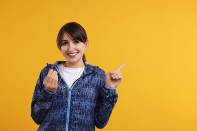 Photo of Happy woman with whistle on orange background, space for text