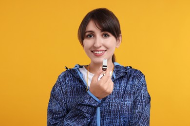 Happy woman with whistle on orange background