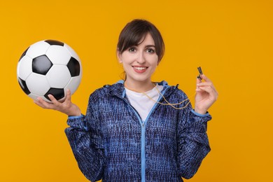 Happy woman with whistle and soccer ball on orange background