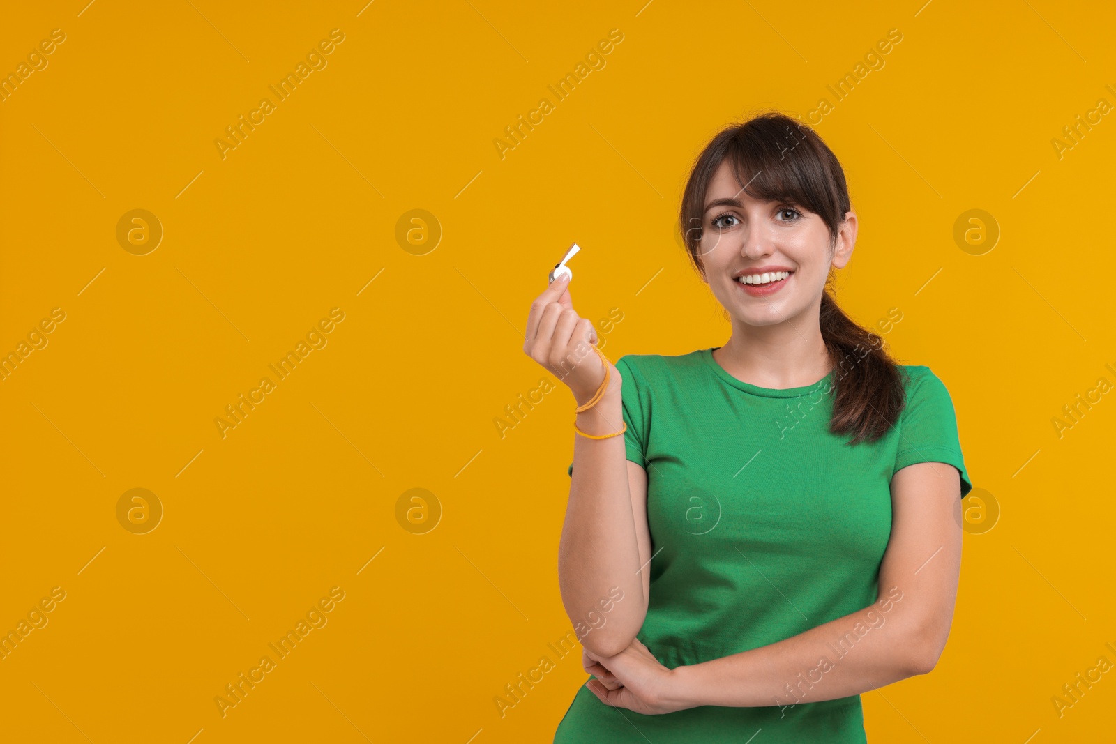 Photo of Happy woman with whistle on orange background, space for text