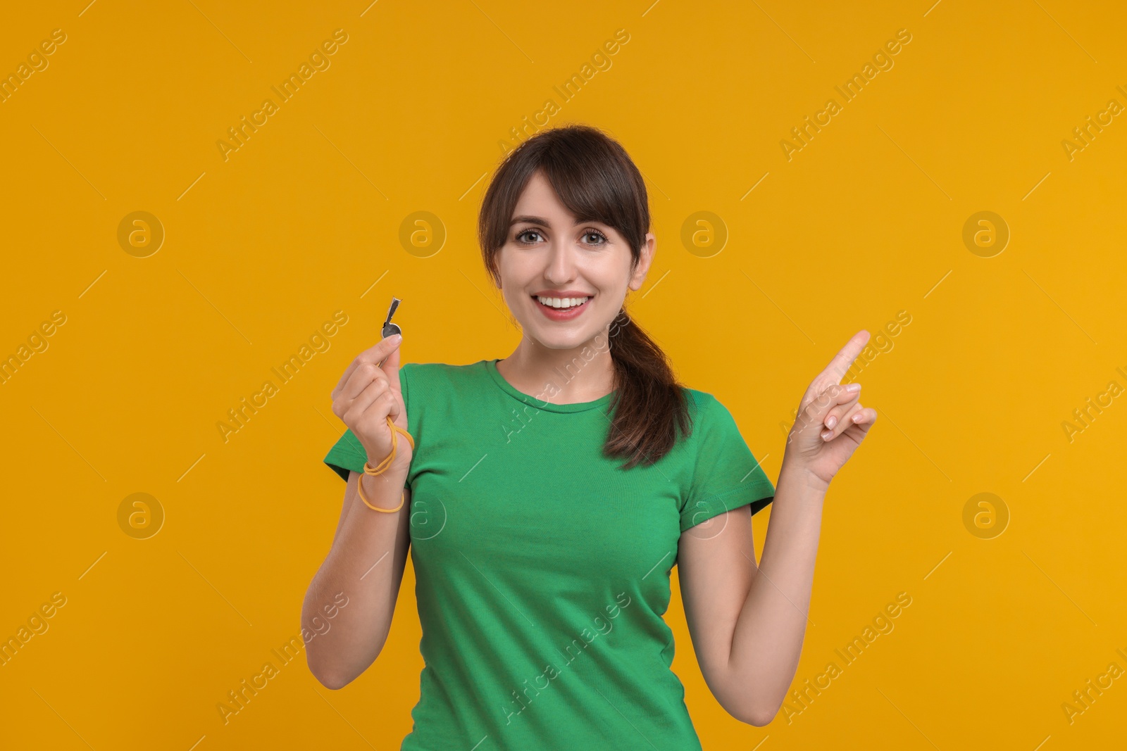 Photo of Happy woman with whistle on orange background