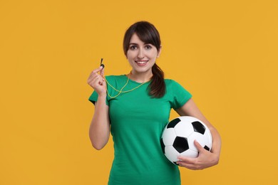 Photo of Happy woman with whistle and soccer ball on orange background