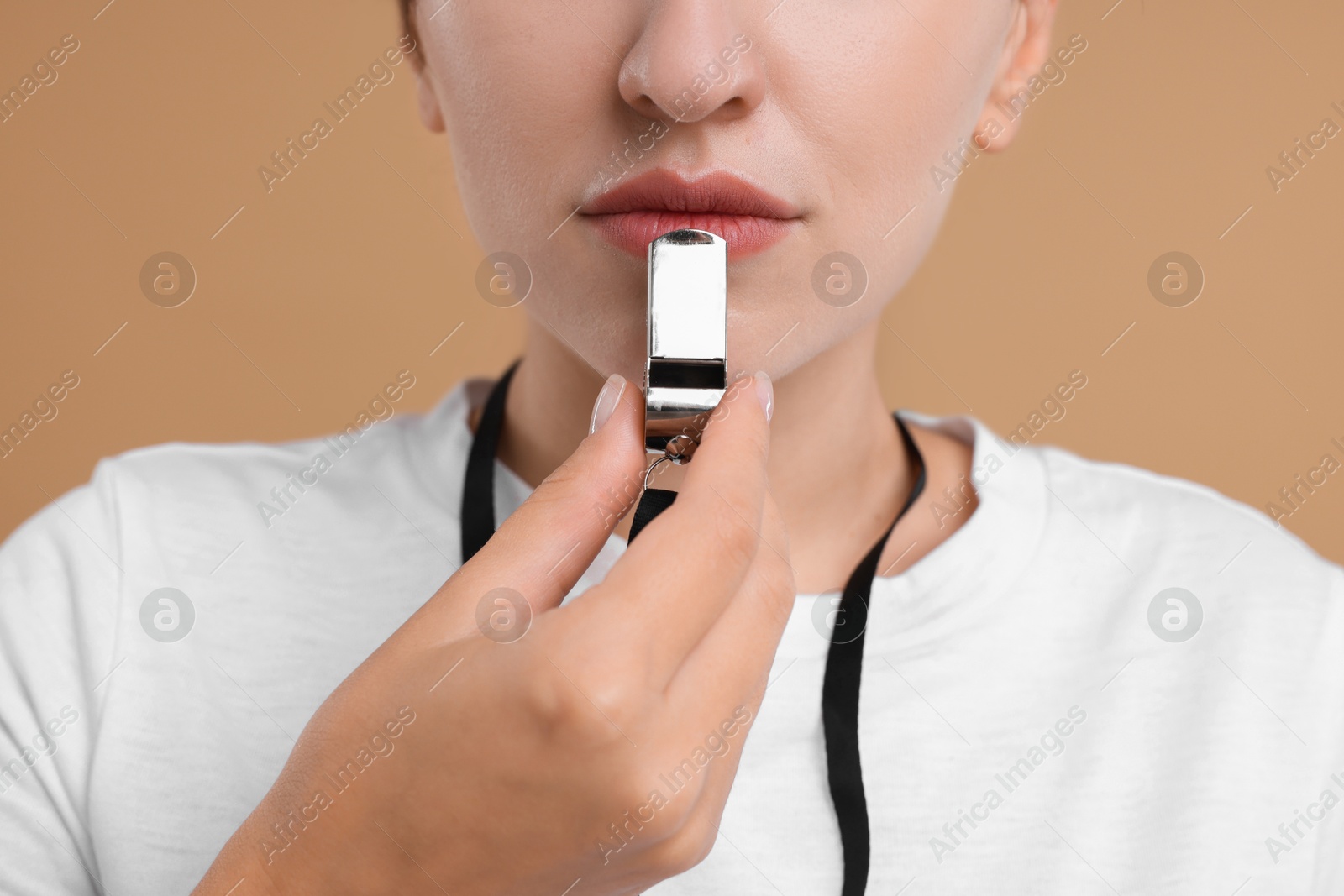 Photo of Woman with whistle on beige background, closeup