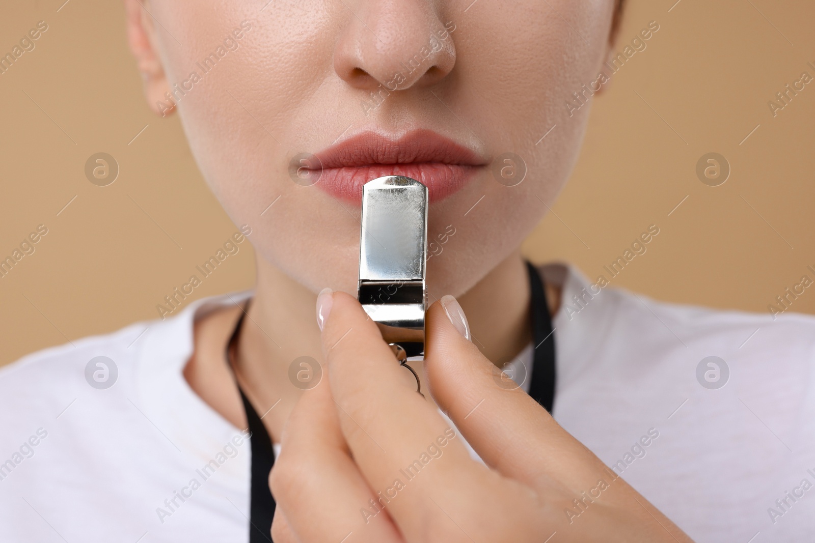 Photo of Woman with whistle on beige background, closeup