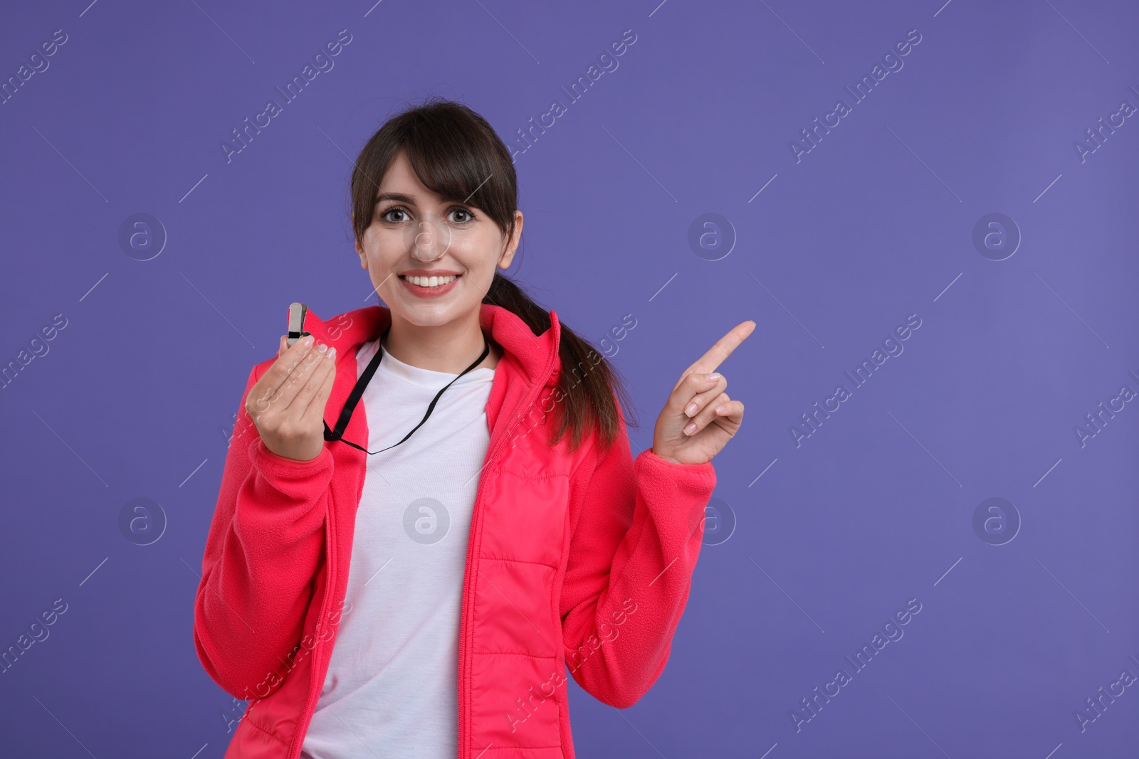 Photo of Happy woman with whistle on purple background, space for text