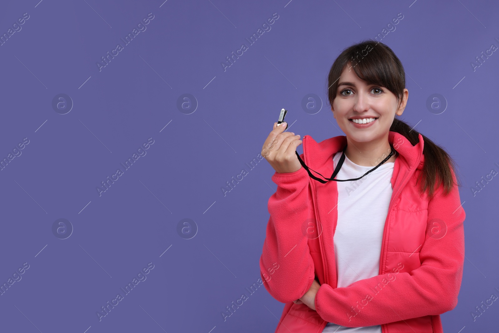 Photo of Happy woman with whistle on purple background, space for text