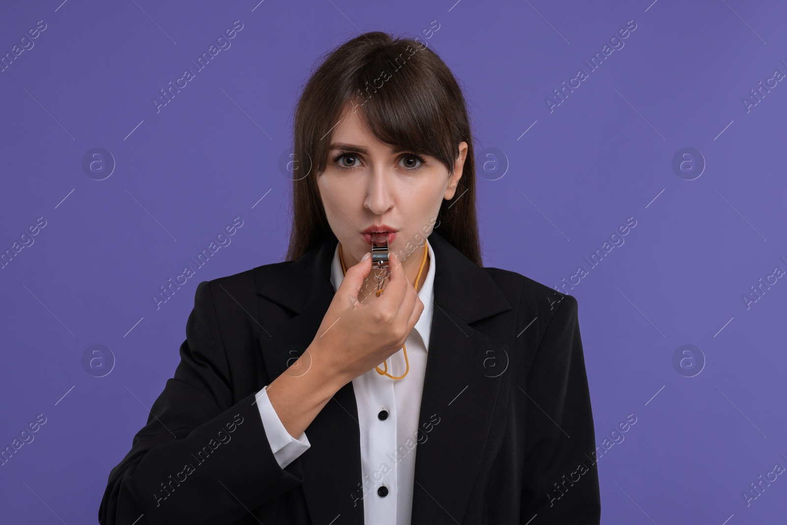 Photo of Young woman blowing whistle on purple background