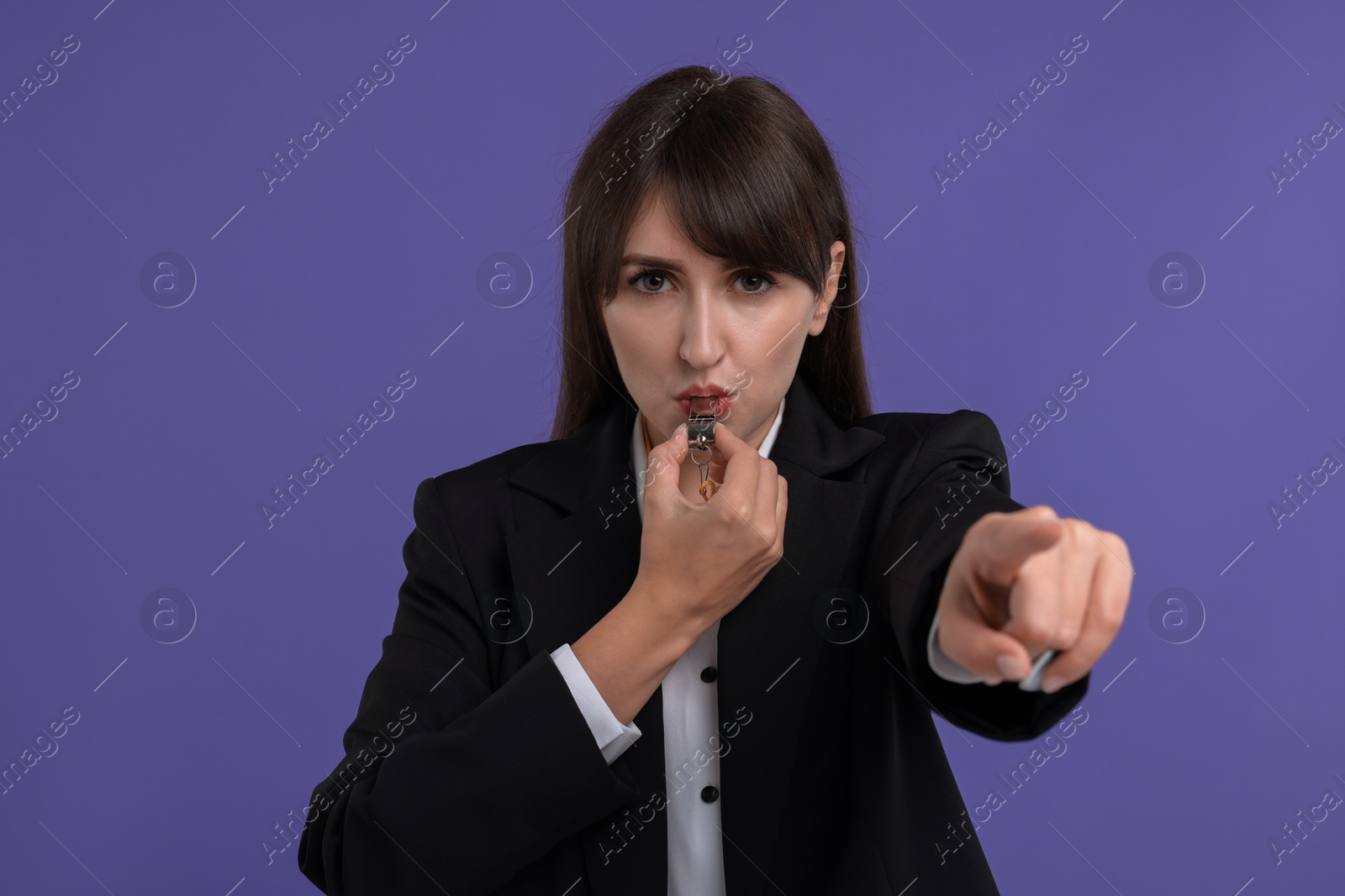 Photo of Young woman blowing whistle on purple background