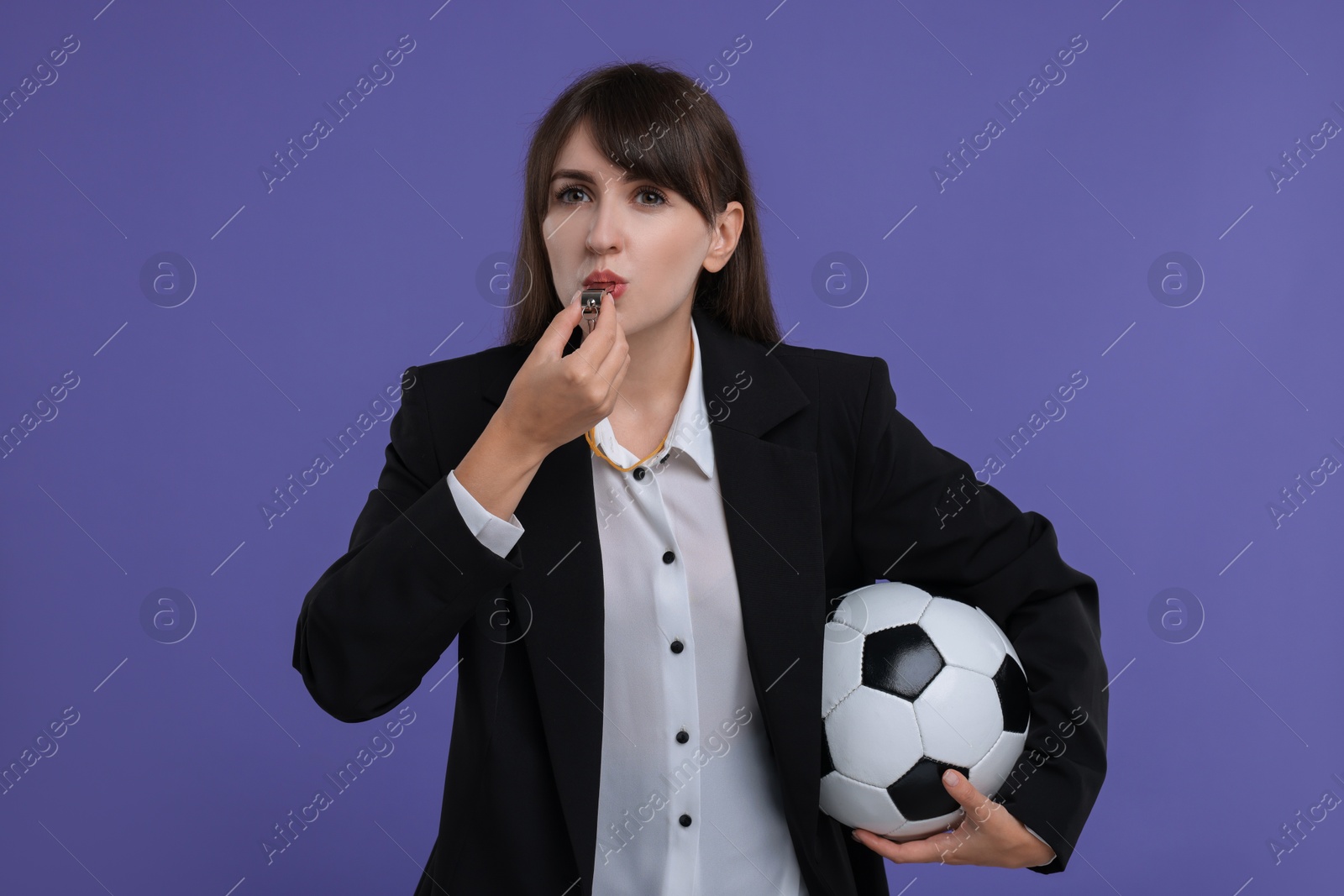 Photo of Woman with soccer ball blowing whistle on purple background