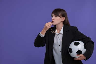 Photo of Woman with soccer ball blowing whistle on purple background, space for text