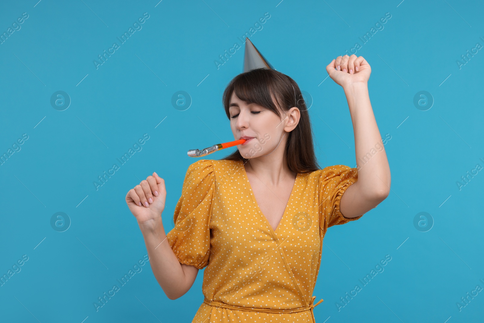 Photo of Woman in party hat with blower on light blue background