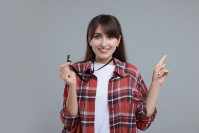 Happy woman with whistle on grey background