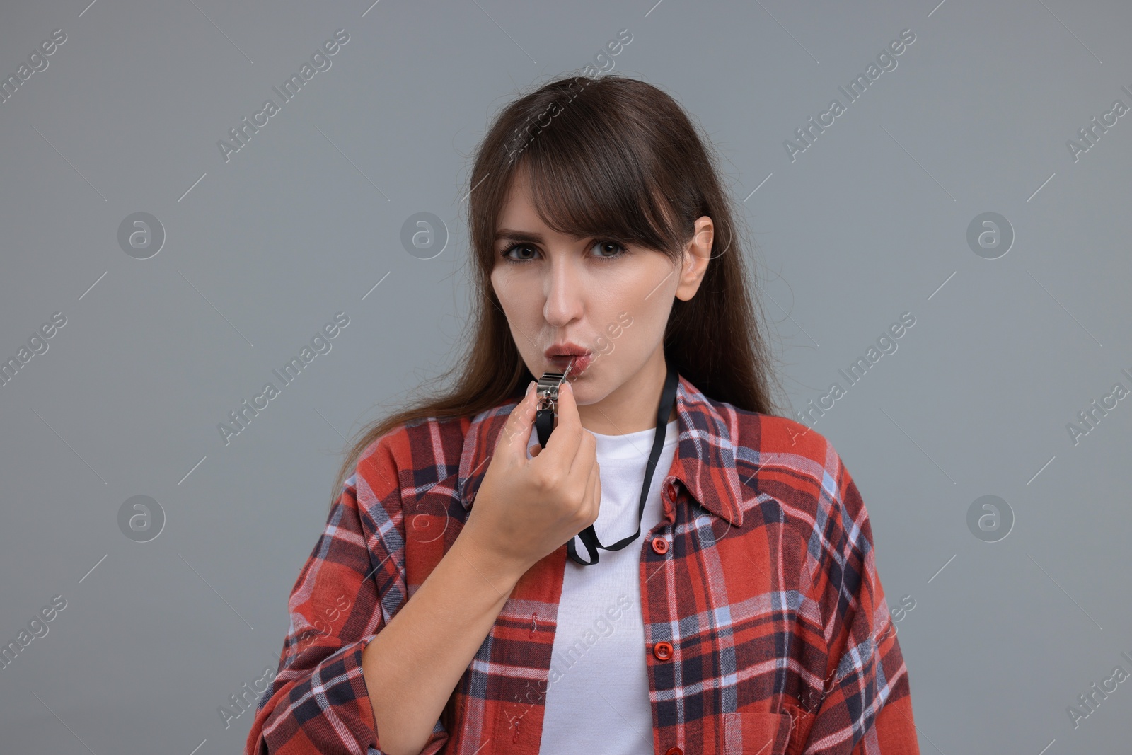 Photo of Young woman blowing whistle on grey background