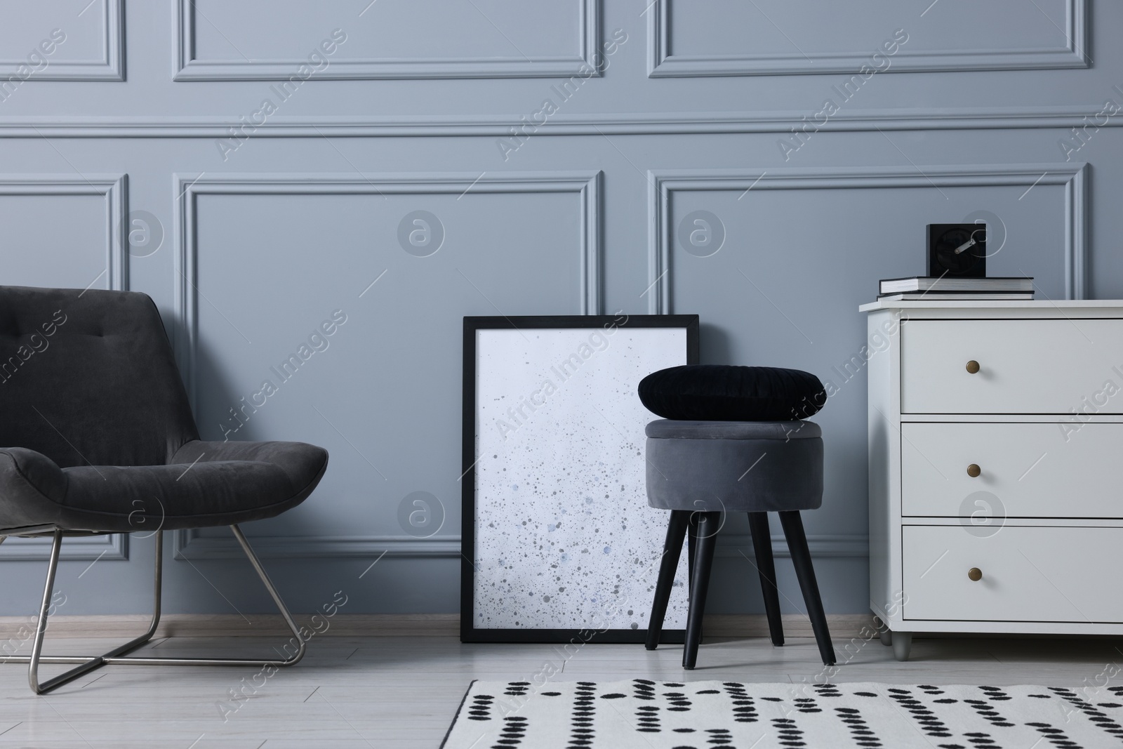 Photo of Stylish interior with stool and chest of drawers near light grey wall