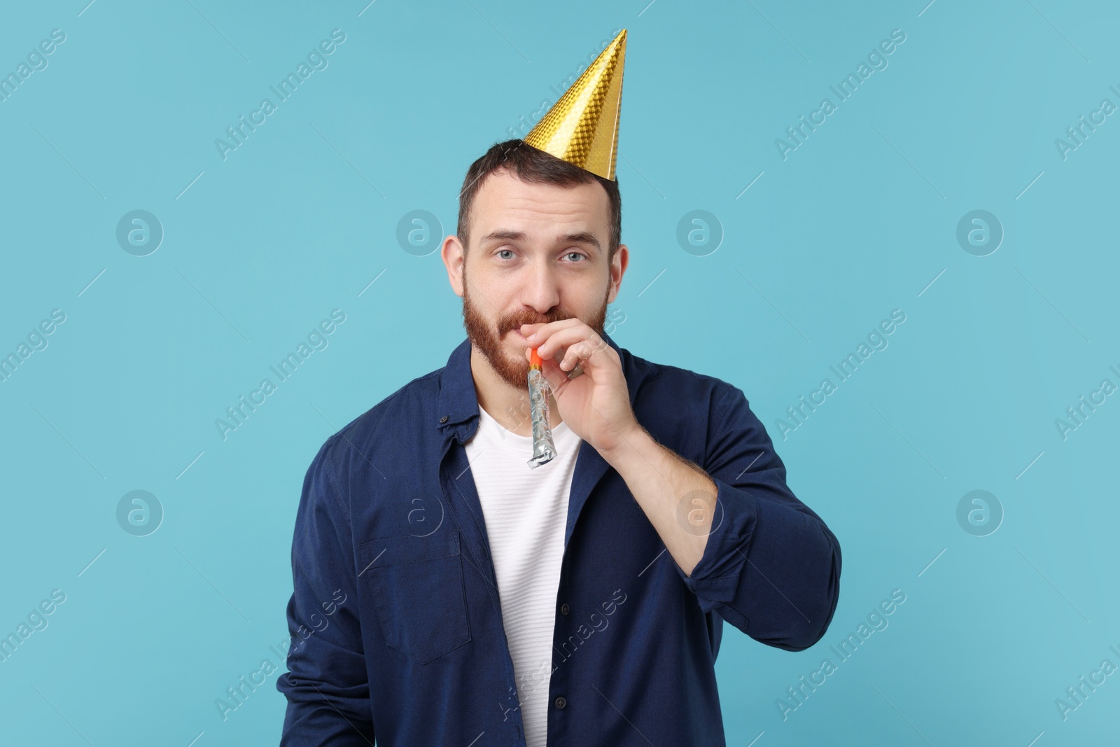 Photo of Man in party hat with blower on light blue background