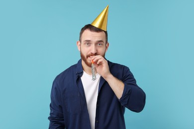 Man in party hat with blower on light blue background