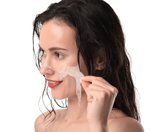 Smiling woman peeling off face mask on white background