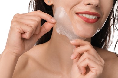 Photo of Smiling woman peeling off face mask on white background, closeup