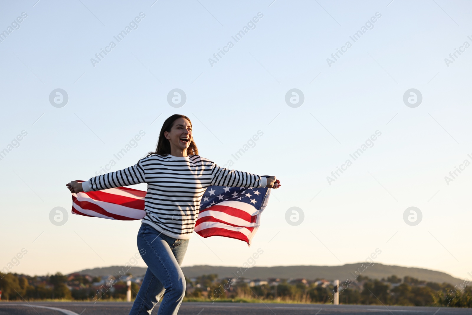 Photo of Happy woman with flag of USA running outdoors. Space for text