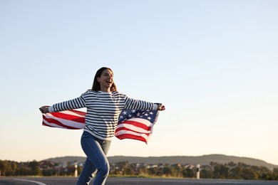 Happy woman with flag of USA running outdoors. Space for text